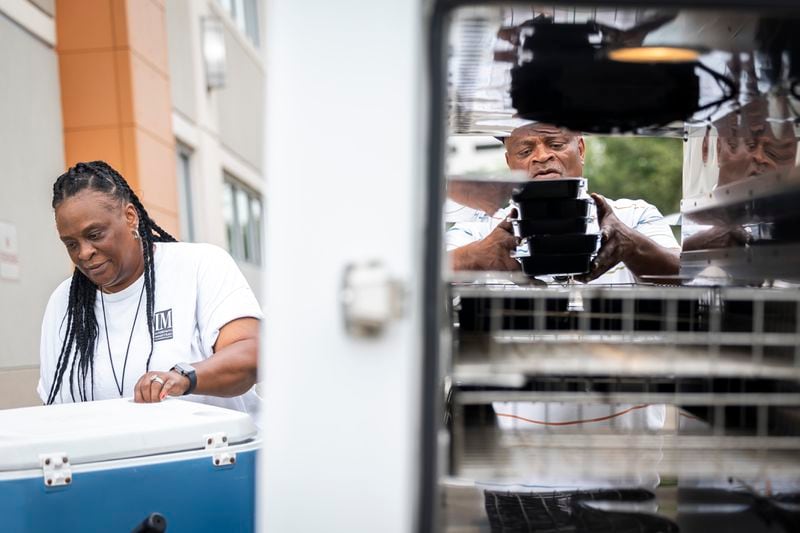 Tracey Hill and Napier Williams load hot meals into a Meals on Wheels delivery truck, Friday, July 12, 2024, in Houston. They have many clients who rely on food delivery but also human connection provided by Meals on Wheels employees. (AP Photo/Annie Mulligan)