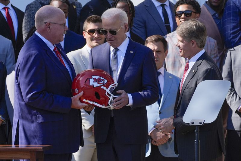 Kansas City Chiefs head coach Andy Reid, left, presents President Joe Biden, center, with a Chiefs helmet Kansas City Chiefs CEO Clark Hunt, right, watches during an event with the Super Bowl-champion Chiefs on the South Lawn of the White House, Friday, May 31, 2024, to celebrate their championship season and victory in Super Bowl LVIII. (AP Photo/Evan Vucci)