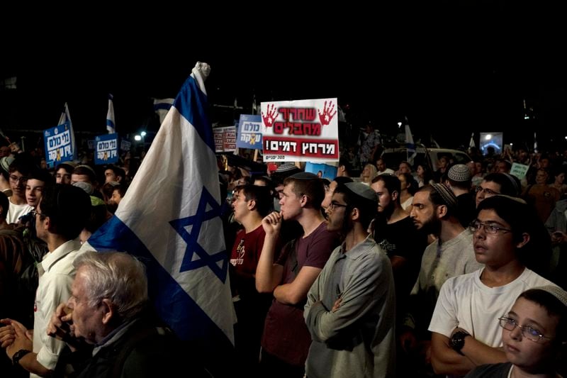 Right-wing Israelis with relatives held hostage by Hamas in the Gaza Strip, and their supporters, rally against a hostage deal, in Jerusalem, Thursday, Sept. 19, 2024. The placard in Hebrew reads: " To bathe in his blood." (AP Photo/Maya Alleruzzo)