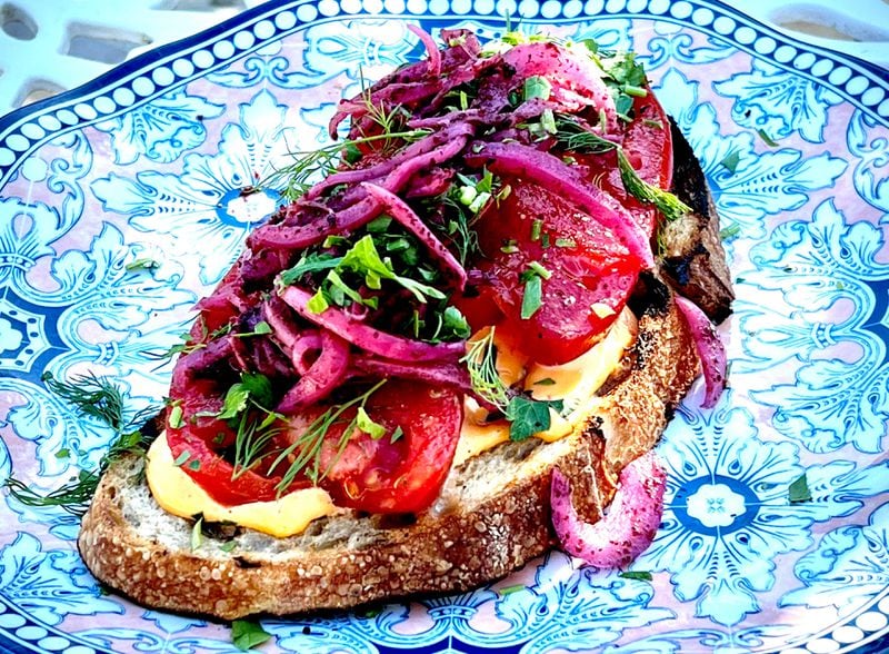 Tomato toast — with hummus, pickled onions and herbs — was a recent special at Daily Chew. Henri Hollis for The Atlanta Journal-Constitution
