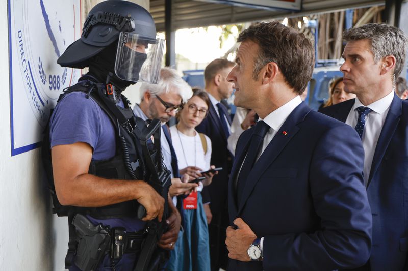 French President Emmanuel Macron talks to a policeman upon his arrival at the central police station in Noumea, New Caledonia, Thursday, May 23, 2024. Macron has met with local officials in riot-hit New Caledonia, after crossing the globe in a high-profile show of support for the French Pacific archipelago gripped by deadly unrest.(Ludovic Marin/Pool Photo via AP)