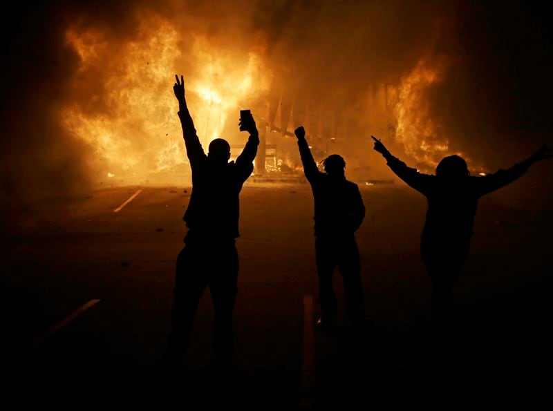 FILE - People watch as stores burn on Nov. 25, 2024, in Ferguson, Mo. In Ferguson itself, residents protested not only Michael Brown’s death but also years if not decades of mistreatment by police and city officials. (AP Photo/David Goldman, File)