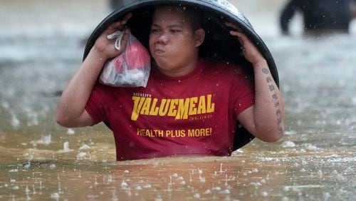 A resident uses a laundry tub to protect him from rain as he wades along a flooded street caused by Tropical Storm Yagi, locally called Enteng, on Monday, Sept. 2, 2024, in Cainta, Rizal province, Philippines. (AP Photo/Aaron Favila)