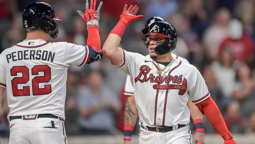 Braves left fielder Joc Pederson (22) high-fives Braves catcher William Contreras (24) after hitting a home run in the fourth inning at Truist Park on Saturday, Oct. 2, 2021. (Daniel Varnado/For the Atlanta Journal-Constitution)