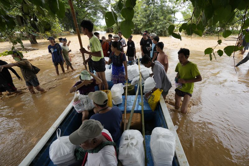 Volunteers gather to distribute foods to flood victims on a flooded road in Naypyitaw, Myanmar, Saturday, Sept. 14, 2024. (AP Photo/Aung Shine Oo)