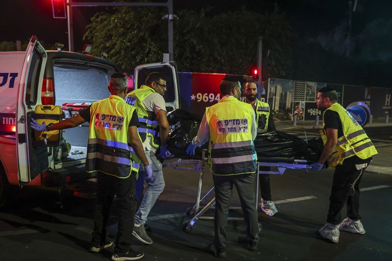 Members of Zaka Rescue and Recovery team load a dead person into an ambulance following a shooting attack in Jaffa, a mixed Arab-Jewish area of Tel Aviv, Israel, Tuesday, Oct. 1, 2024. (AP Photo/Itai Ron)