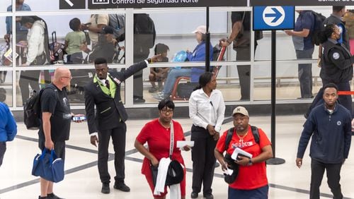 Airport customer service's Ebou John (center-left) helps a traveler with directions. Travelers swelled Atlanta's Hartsfield-Jackson International Airport on Friday, May 24, 2024. (John Spink/AJC)