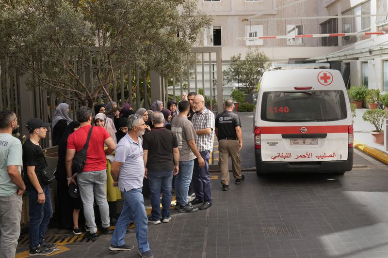 Lebanese Red Cross ambulance passes next of the families of victims who were injured on Monday by their exploding handheld pagers, at the emergency entrance of the American University hospital, in Beirut, Lebanon, Wednesday, Sept. 18, 2024. (AP Photo/Hussein Malla)