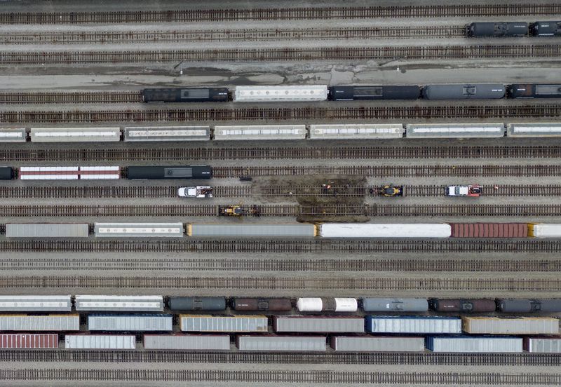 Train cars are seen on the tracks in an aerial view at Canadian National Rail's Thornton Yard as the Port Mann Bridge spans the Fraser River and trucks transport cargo containers on the highway in Surrey, British Columbia, Canada, Thursday, Aug. 22, 2024. (Darryl Dyck/The Canadian Press via AP)