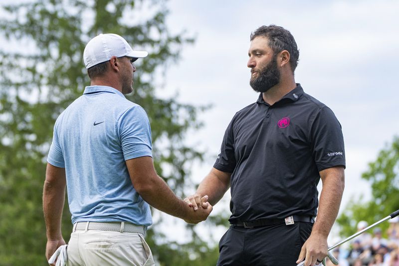 Captain Brooks Koepka, left, of Smash GC, shakes hands with captain Jon Rahm, of Legion XIII, on the 18th green during the final round of LIV Golf Greenbrier at The Old White at The Greenbrier, Sunday, Aug. 18, 2024, in White Sulphur Springs, W.Va. (Mike Stobe/LIV Golf via AP)