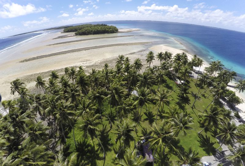 FILE - A section of land between trees is washed away due to rising seas on Nov. 6, 2015, in Majuro Atoll, Marshall Islands. (AP Photo/Rob Griffith, File)