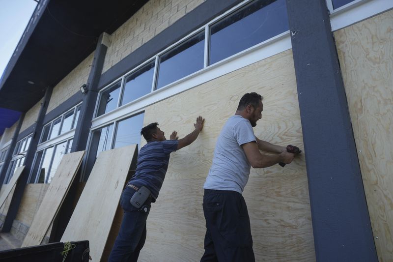 Furniture store employees board up windows for protection ahead of Hurricane Beryl's expected arrival, in Playa del Carmen, Mexico, Wednesday, July 3, 2024. (AP Photo/Fernando Llano)