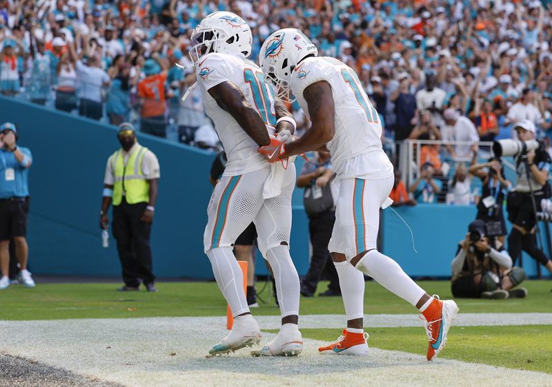 Miami Dolphins wide receiver Tyreek Hill (10) holds his hands behind his back as if he is handcuffed as Miami Dolphins wide receiver Jaylen Waddle (17) unlocks them after Hill scores against the Jacksonville Jaguars in the second half during an NFL football game at Hard Rock Stadium in Miami Gardens, Florida, on Sunday, Sept. 8, 2024. (Al Diaz/Miami Herald via AP)