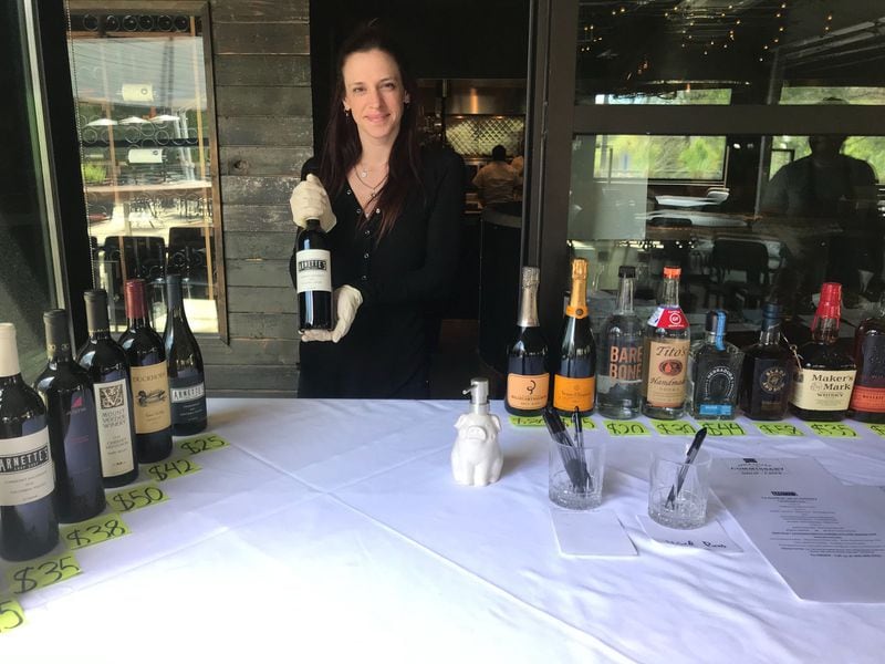 Arnette’s head hostess, Stephanie Cannoles, handles customer orders for pickup. A checkout table in the covered patio has been placed in front of the dining room entrance as a barrier between customers and staff. LIGAYA FIGUERAS / LIGAYA.FIGUERAS@AJC.COM