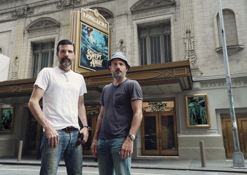 Scott Avett, left, and his brother, Seth, pose outside the Longacre Theater in New York where the Broadway musical “Swept Away,” that uses their music, begins previews in late October. The Avett Brothers are the latest example of alternative rock music to invade the world of stage musical. (Emilio Madrid/DKC O&M via AP)