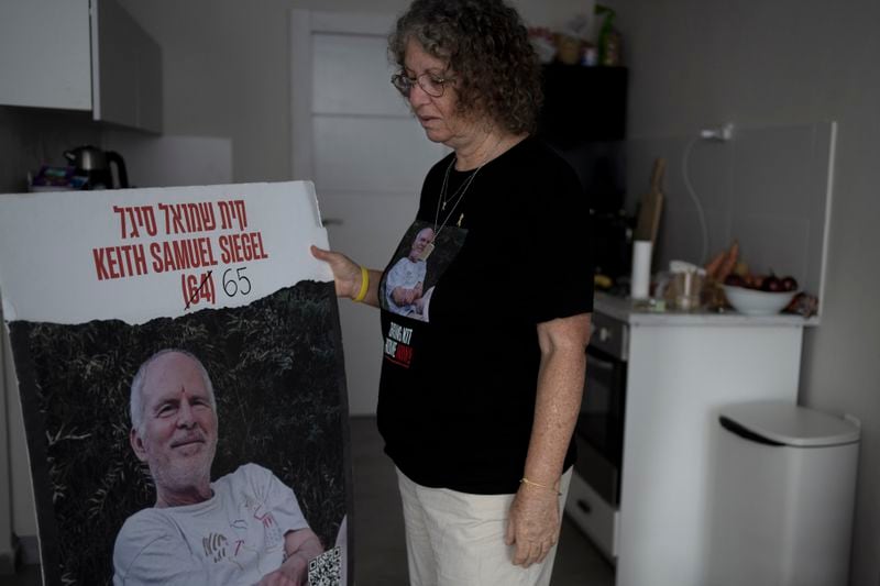 Aviva Siegel, who was held hostage by Hamas in the Gaza Strip for 51 days after she was kidnapped with her husband on Oct. 7, holds a poster of her husband, Keith, who is still in captivity, in Tel Aviv, Israel, Sunday, Sept. 29, 2024. (AP Photo/Maya Alleruzzo)