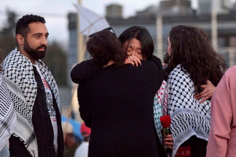 Sue Han, facing, is hugged after speaking of her friend, the 26-year old Aysenur Ezgi Eygi, killed recently in the occupied West Bank, during vigil on Alki Beach, Wednesday, Sept. 11, 2024, in Seattle. Eygi grew up in Seattle, attended Seattle Public Schools and graduated from the University of Washington. Left is another friend Yoseph Ghazal, who also spoke. (AP Photo/John Froschauer)