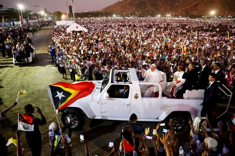 Pope Francis waves as he's driven through a crowd of estimated 600,000 people after presiding over a mass in the seaside park of Tasitolu near Dili, East Timor, Tuesday, Sept. 10, 2024. With half of East Timor's population gathered at a seaside park, Francis couldn't help but oblige them with a final good night and languid loops in his popemobile, long after the sun had set and the field was lit by cellphone screens. (Willy Kurniawan/Pool Photo via AP)