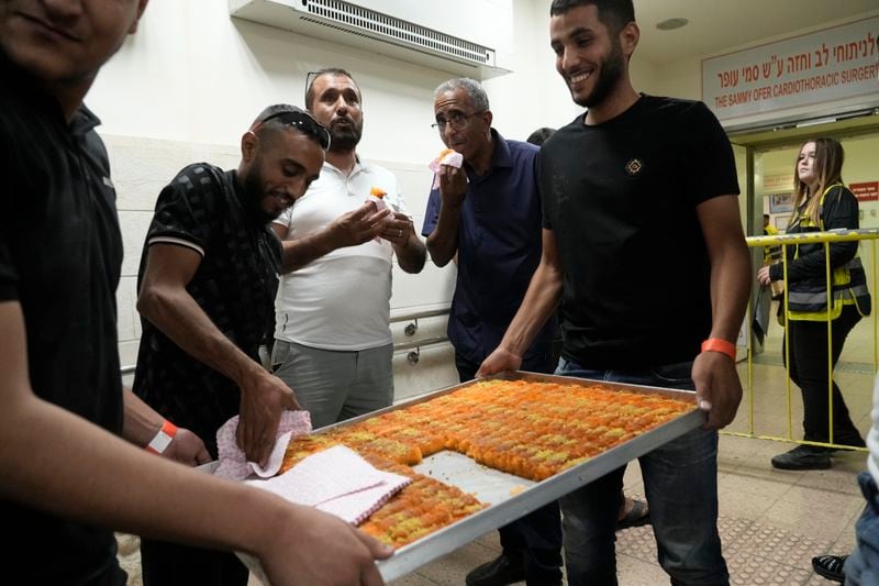 Friends and relatives of Qaid Farhan Alkadi, 52, who was held hostage by Hamas militants in the Gaza Strip, eat a traditional sweet known as knafeh, on a corridor of the Soroka Medical Center in Beersheba, Israel, Tuesday, Aug. 27, 2024. (AP Photo/Tsafrir Abayov)