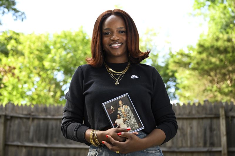 Ferguson activist Brittany Packnett-Cunningham poses for an image while holding a picture of her and her father Rev. Ronald Packnett, Saturday, Sep. 7, 2024, in Mount Rainier, Md. (AP Photo/Terrance Williams)