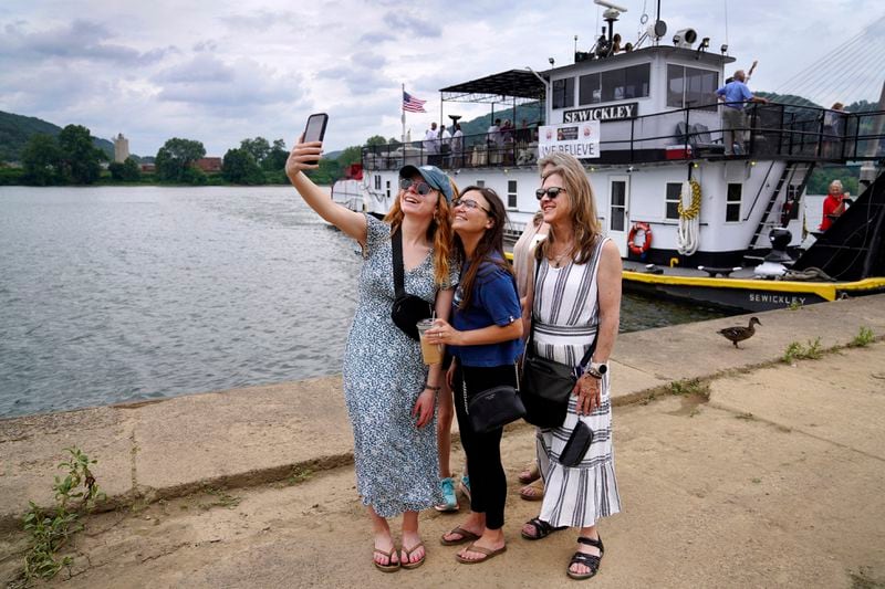 From left, Tara Mostero, her twin sister Ashley Mostero, Becca Eckelkamp, Tracy Mostero, and Jean Hilgendorf take a selfie Sunday, June 23, 2024, in front of the riverboat that will carry the Eucharist down the Ohio River from the Steubenville Marina to Wheeling, W.Va. (AP Photo/Jessie Wardarski)