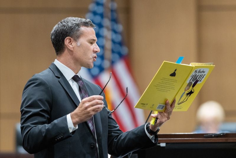 Cobb County teacher Katie Rinderle’s attorney Craig Goodmark reads from a copy of children’s book “My Shadow is Purple” at a hearing at the Cobb County Board of Education in Marietta on Thursday, August 10, 2023. Rinderle is facing termination after reading “My Shadow is Purple,” a book about gender identity, to fifth graders. (Arvin Temkar / arvin.temkar@ajc.com)