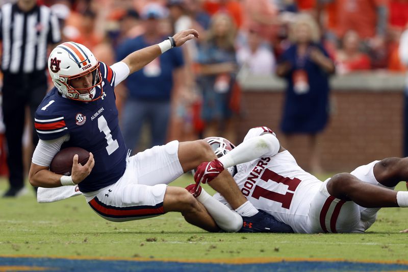 Auburn quarterback Payton Thorne (1) stretches for the first down as \he is tackled by Oklahoma linebacker Kobie McKinzie (11) during the first half of an NCAA college football game, Saturday, Sept. 28, 2024, in Auburn, Ala. (AP Photo/Butch Dill)