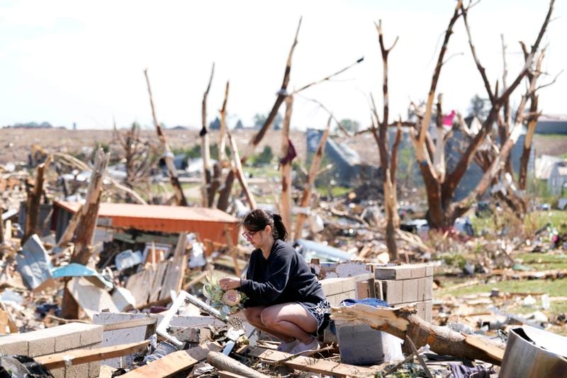 Kimberly Ergish holds flowers as she cleans out belongs from her tornado damaged home, Wednesday, May 22, 2024, in Greenfield, Iowa. (AP Photo/Charlie Neibergall)