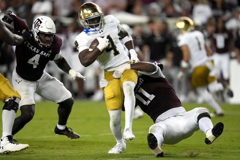 Notre Dame running back Jeremiyah Love (4) breaks a tackle attempt behind the line of scrimmage by Texas A&M defensive lineman Nic Scourton (11) during the fourth quarter of an NCAA college football game Saturday, Aug. 31, 2024, in College Station, Texas. (AP Photo/Sam Craft)