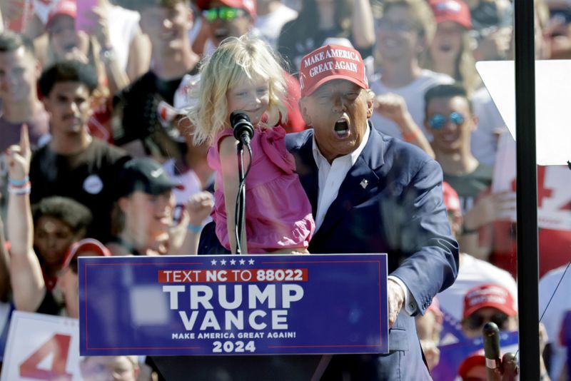 Republican presidential nominee former President Donald Trump holds his granddaughter Carolina Trump as he speaks at a campaign event at Wilmington International Airport in Wilmington, N.C., Saturday, Sept. 21, 2024. (AP Photo/Chris Seward)