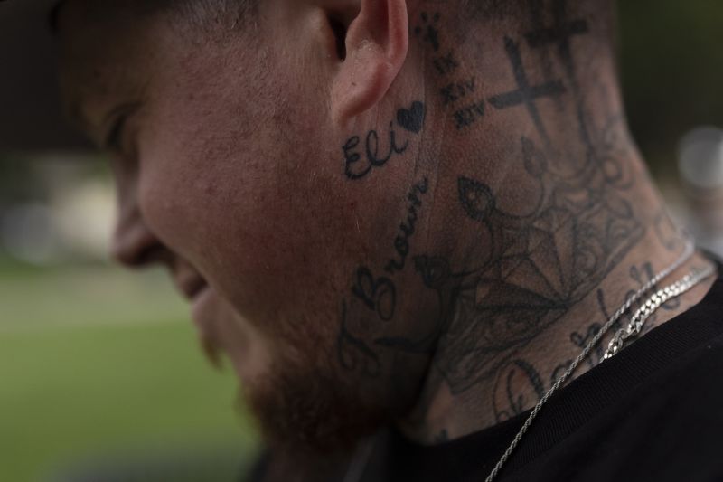 With his stepson's name tattooed below his ear, Tyler Brown, stepfather of Elijah Ott, who died of a fentanyl overdose at 15, looks at a park bench dedicated to Elijah in Paso Robles, Calif., Friday, Aug. 2, 2024. (AP Photo/Jae C. Hong)