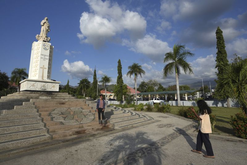 A girl stands for a photograph in front of the Virgin Mary Statue in Dili, East Timor, Tuesday, Aug. 13, 2024. (AP Photo/Achmad Ibrahim)