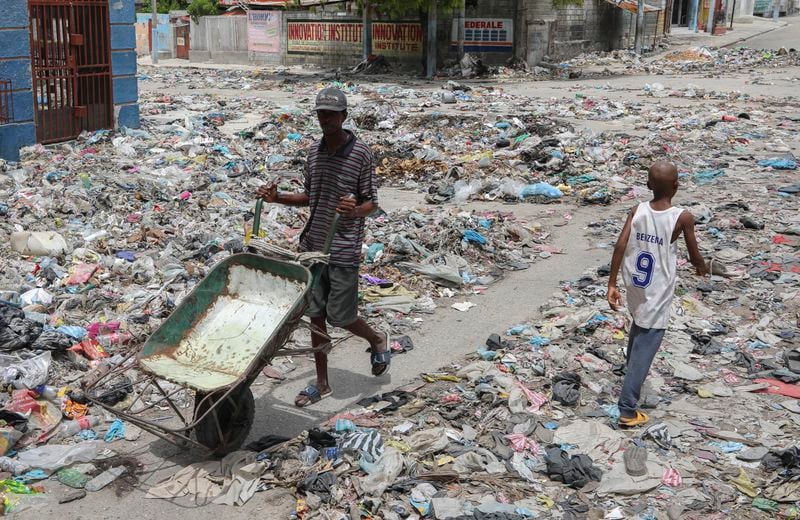 People walk down a street covered with trash in downtown Port-au-Prince, Haiti, Thursday, Sept. 5, 2024. (AP Photo/Odelyn Joseph)