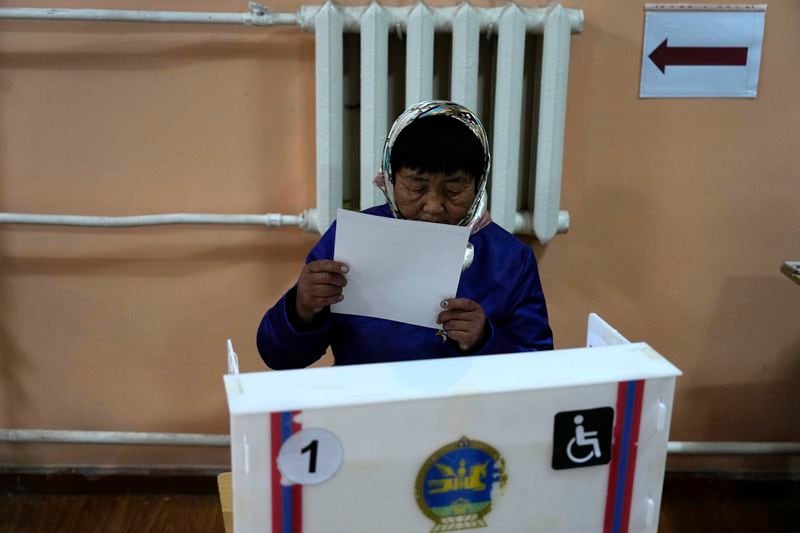 A voter examines her vote at a polling station in the Ger District on the outskirts of Ulaanbataar, Mongolia, Friday, June 28, 2024. Voters in Mongolia are electing a new parliament on Friday in their landlocked democracy that is squeezed between China and Russia, two much larger authoritarian states. (AP Photo/Ng Han Guan)