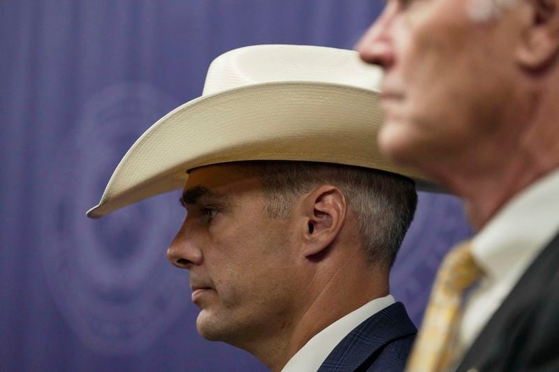 Ryan Christian, with the Texas Rangers, left, stands alongside First Assistant/Chief of Courts David Mitcham, right, as Harris County District Attorney Kim Ogg, not pictured, announces corruption charges related to 2022 Election during a press conference on Tuesday, Aug. 13, 2024, in Houston. (Raquel Natalicchio/Houston Chronicle via AP)