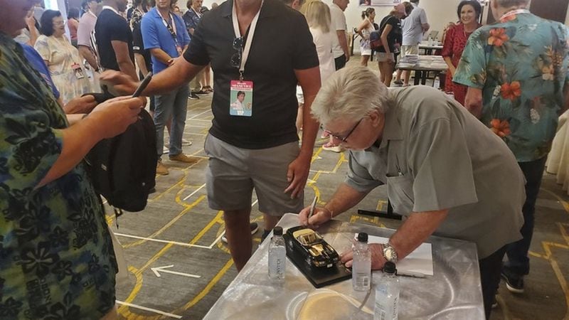 Fans gathered at the Royal Palm South Beach in Miami Beach, Fla., on Friday, Sept. 13, 2024, to celebrate the 40th anniversary of the television series "Miami Vice." Actor Bruce McGill, who guest-starred as retired detective Hank Weldon in the show's second season, signs a model Ferrari for a fan. (AP Photo/David Fischer)