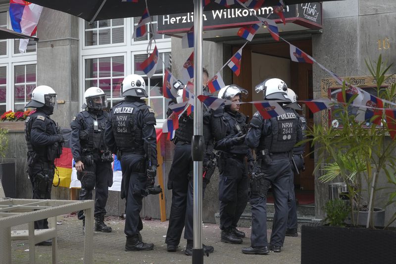 Police stand next to a restaurant decorated with Serbian flags ahead the Group C match between Serbia and England at the Euro 2024 soccer tournament in Gelsenkirchen, Germany, Sunday, June 16, 2024. (AP Photo/Markus Schreiber)