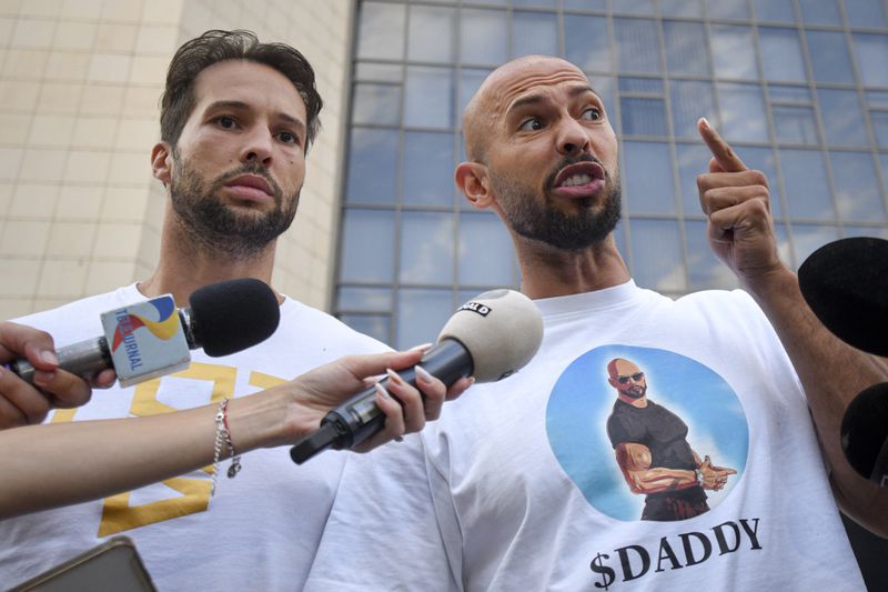 Andrew Tate speaks to media next to his brother Tristan, left, outside the Bucharest Tribunal after being placed under house arrest, in Bucharest, Romania, Thursday, Aug. 22, 2024. A court in Romania's capital on Thursday placed the divisive internet influencer Andrew Tate under house arrest for 30 days, as prosecutors investigate a sprawling new case that involves allegations of human trafficking of minors and sex with a minor. (AP Photo/Alexandru Dobre)