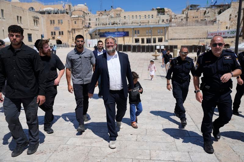 Israel's far-right National Security Minister Itamar Ben-Gvir, center, flanked by his security detail, approach the entrance to Jerusalem's most sensitive holy site, which Jews revere the site as the Temple Mount, believed to be the location of the First and Second Temples, and it is a holy site for Muslims as Haram al-Sharif or the Noble Sanctuary, in the Old City, Tuesday, Aug. 13, 2024. (AP Photo/Ohad Zwigenberg)