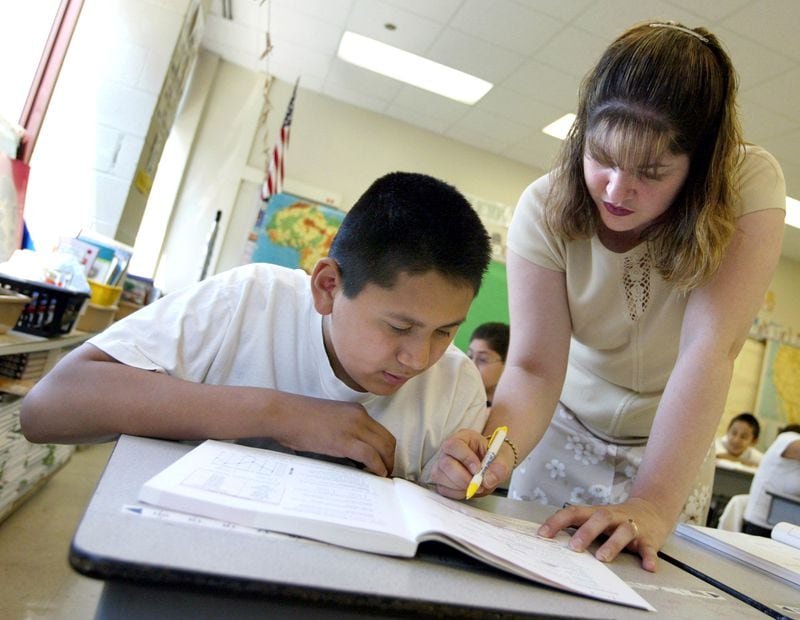 CHICAGO, IL - JULY 2: Teacher Blanca Feliciano assists a student in her sixth-grade class during summer school July 2, 2003 in Chicago, Illinois. A record number of students are expected at summer school due to a strong showing for a new voluntary program for mid-tier students and strict application of non-ITBS (Iowa Tests of Basic Skills) test promotion standards. (Photo by Tim Boyle/Getty Images)