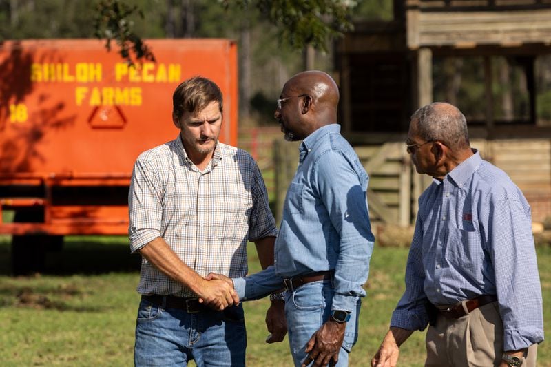 Democratic U.S. Sen. Raphael Warnock, center, greets pecan farmer Buck Paulk at his property Thursday in Ray City as part of President Joe Biden's tour of damage in the area from Hurricane Helen. (Arvin Temkar / AJC)
