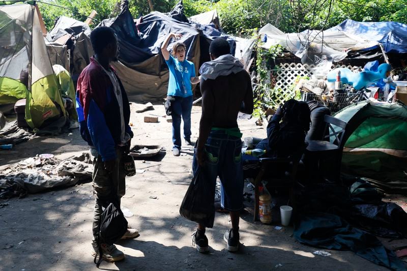 Tracy Woodard (center) asks residents of the Cooper Street encampment about a missing person on Monday, Aug. 12, 2024. (Miguel Martinez / AJC)