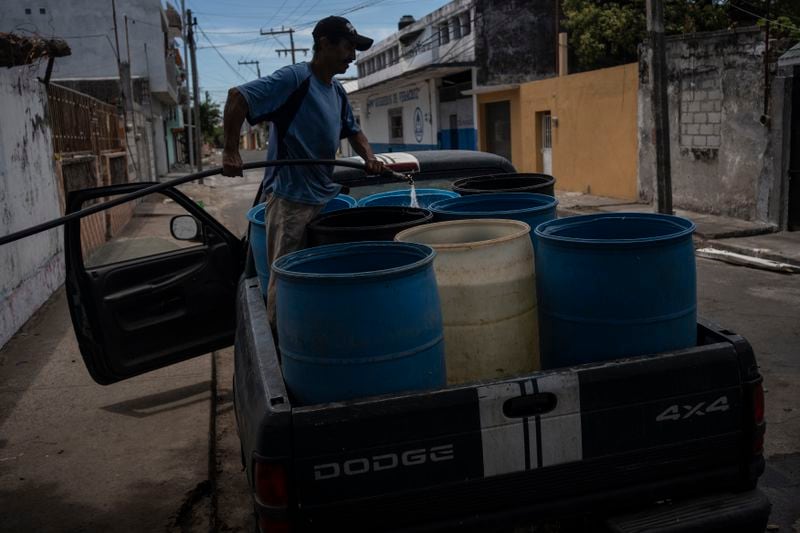 A man fills containers with water due to the shortage caused by high temperatures and drought in Veracruz, Mexico, on June 16, 2024. Human-caused climate change intensified and made far more likely this month's killer heat with triple digit temperatures, a new flash study found Thursday, June 20. (AP Photo/Felix Marquez)