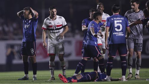 Juan Izquierdo of Uruguay's Nacional, bottom, lies on the pitch after collapsing during a Copa Libertadores soccer game against Brazil's Sao Paulo at Morumbi stadium in Sao Paulo, Thursday, Aug. 22, 2024. (AP Photo/Ettore Chiereguini)