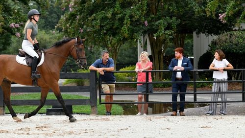 Kyle Hester (left) and his wife Cindy discuss with neighbors Ben Leonard and Christy Hayes (right) as Nicole Stringer (foreground) rides on jumping race horse Leo at Hester’s horse farm home. The Hesters train young horses for competition.  (Hyosub Shin / Hyosub.Shin@ajc.com)