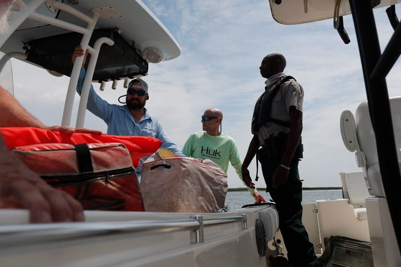 Game Warden Quintin Reed talks with boaters to make sure they have enough life jackets and space on their boat during a safety inspection on the Bull River.