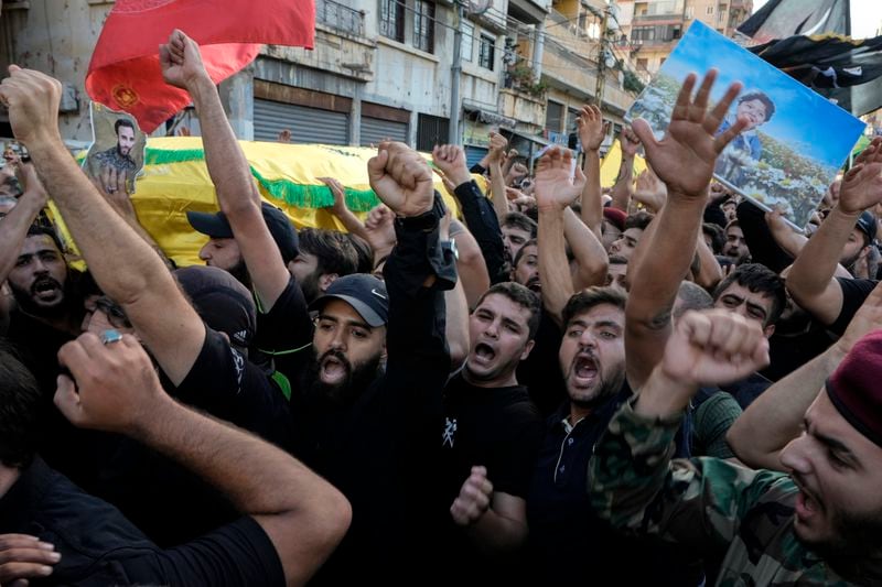 Mourners chant slogans as they carry the coffins of Hezbollah fighters who were killed in Friday's Israeli strike, during their funeral procession in the southern suburb of Beirut, Lebanon, Saturday, Sept. 21, 2024. (AP Photo/Bilal Hussein)