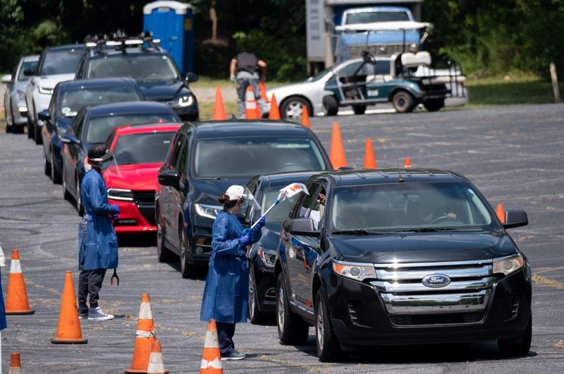 200716-Atlanta-Workers at a CORE testing site at Antioch Baptist Church North in Northwest Atlanta collect covid-19 tests from a line of cars that disappears and wraps around the block Thursday afternoon July 16, 2020. Ben Gray for the Atlanta Journal-Constitution