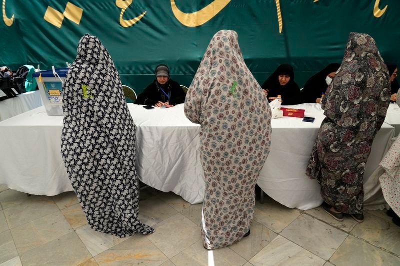 Women get their ballot paper during the Iranian presidential election in a polling station at the shrine of Saint Saleh in northern Tehran, Iran, Friday, June 28, 2024. Iranians were voting Friday in a snap election to replace the late President Ebrahim Raisi, killed in a helicopter crash last month, as public apathy has become pervasive in the Islamic Republic after years of economic woes, mass protests and tensions in the Middle East. (AP Photo/Vahid Salemi)