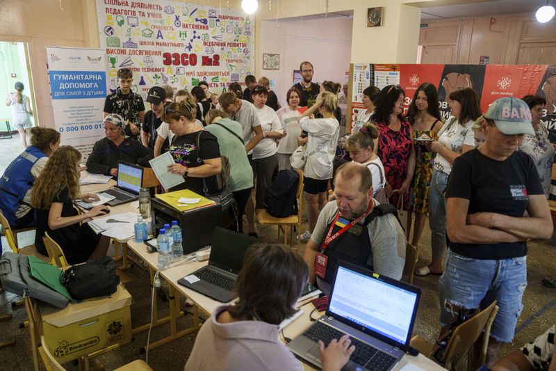 People line up to register for evacuation in Pokrovsk, Donetsk region, Ukraine, Friday, Aug. 23, 2024. (AP Photo/Evgeniy Maloletka)